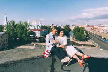 Obraz premium Young couple standing on the roof of the newly-married couple with glasses of champagne in their hands