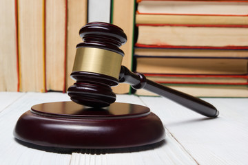 Law book with wooden judges gavel on table in a courtroom or law enforcement office.