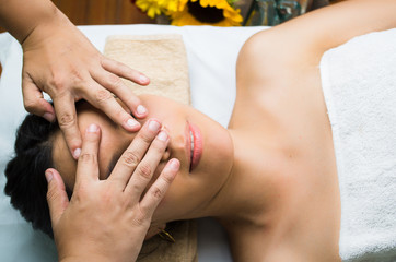 Hispanic brunette model getting massage spa treatment, hands covering womans face