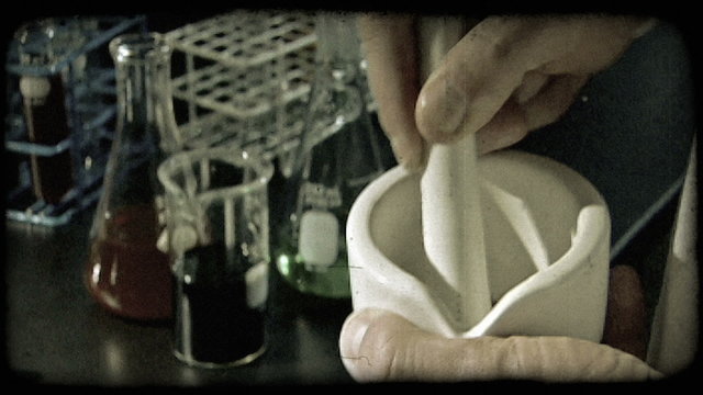 Man crushes granules in a lab. Vintage stylized video clip.