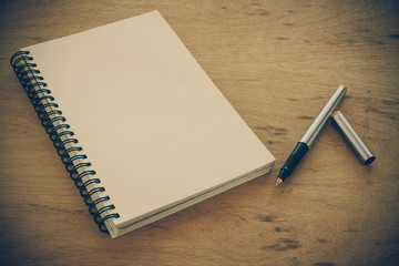 paper notebook and pen on a table with filter effect retro vinta