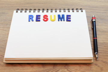 Wood colorful letter word resume lay down notebook on wood backg