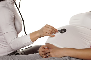 Doctor listening with the stethoscope stomach of the pregnant woman