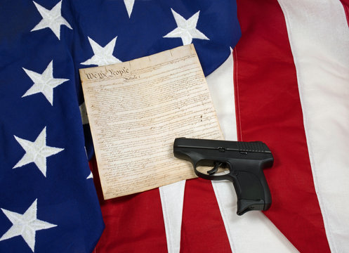 Constitution with Hand Gun on American Flag. Horizontal