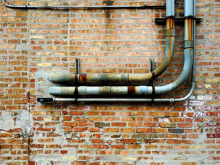 Rusted pipes against brick wall