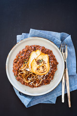 Chocolate risotto served with caramelized onion rings and caramelized pear slices