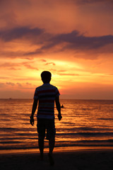 Silhouette of the man, walking on the beach