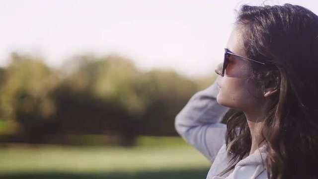 Beautiful girl wearing sunglasses in a field, close up, slow motion