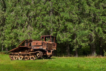 Fototapeta premium abandoned skidder against the backdrop of an ancient forest