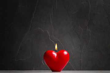 Świeczka w kształcie serca na kamiennym tle 