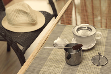 Morning coffee served in vietnam coffee filter on rattan table with a hat on table
