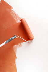 Paint roller applying paint on white wall, home improvements