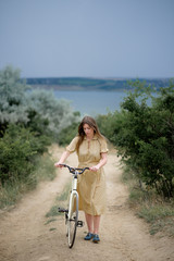 Beautiful brunette standing near her yellow bicycle