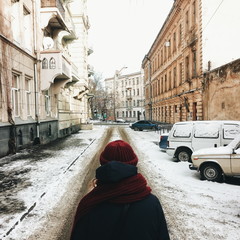 Girl walking by the snowy street in old town