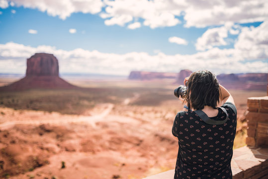 Tourist photographer woman taking pictures photo in Monument Valley, Arizona, USA. Young woman on travel in United States.