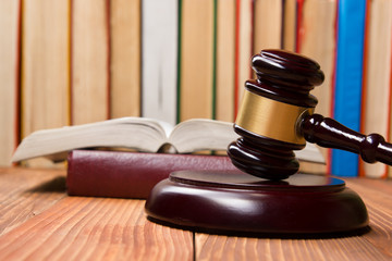 Law book with wooden judges gavel on table in a courtroom or law enforcement office.