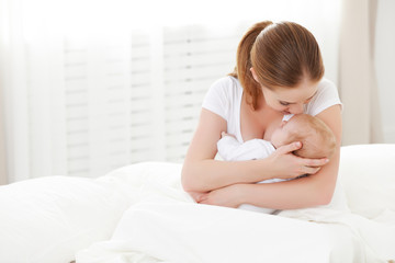 happy family newborn baby in embrace mother in white