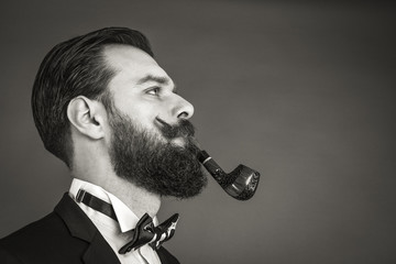 Portrait of a fashionable young man with retro look smoking pipe