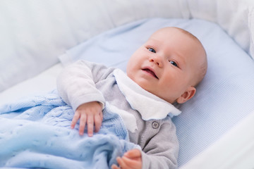 Baby boy in a crib under knitted blanket