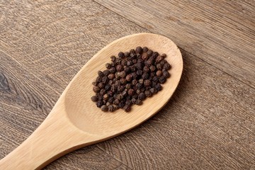 Yellow bell pepper black pepper on wooden spoon