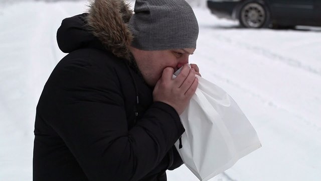 Stressful man breathe into paper bag on snowy road