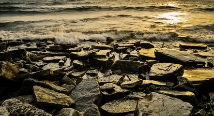 Rocky Sunset Shore. Panorama of the golden setting sun reflects on the rocky shore of Lake Michigan 