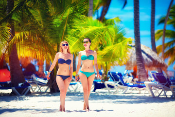 happy young girls walking on tropical beach, during summer vacation