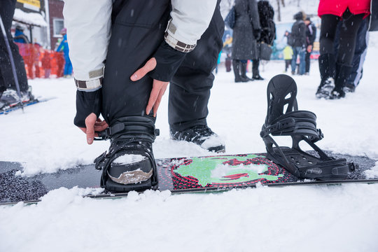 Person putting on his snowboard
