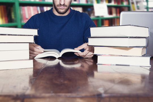 uomo legge libri in biblioteca