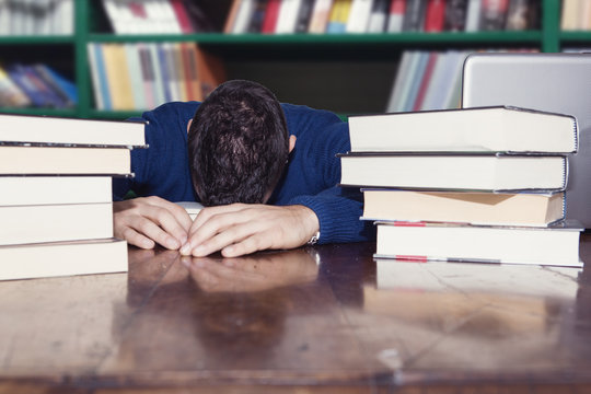 uomo legge libri in biblioteca 