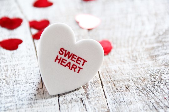 White heart on wooden background with sweet heart text