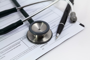 Close-up pen and stethoscope on blank Patient information