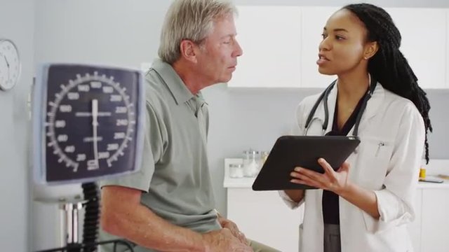 Black woman doctor talking with senior patient in the office