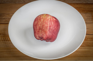Red apple in white dish on wooden background