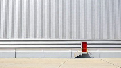 the sheet metal factory wall with the red door entrance