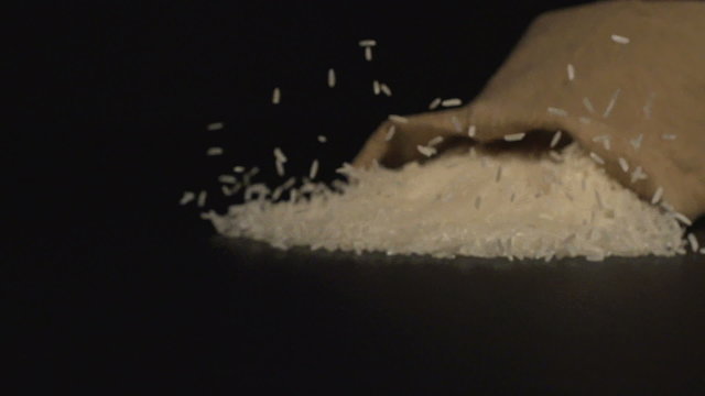SLOW (240fps): A cloth bag falls on a table and a white rice scatter out it
