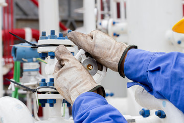 Closeup hands opening valve in petrochemical plant.