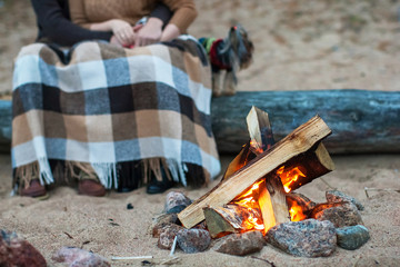 couple sitting on a log by the fire on the rocky beach