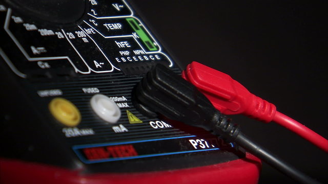Close up of 2 cables plugging into an electrical tester.