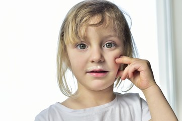 Portrait of a little girl with milk moustaches.