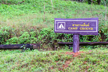CAMP GROUND in Thai and English on wooden sign.