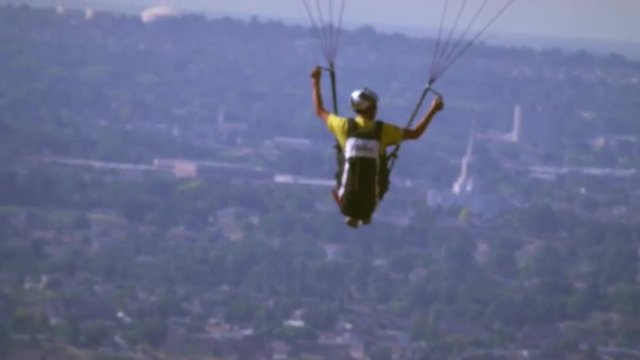 Shot of paragliding man rising above the view of Salt Lake Valley.