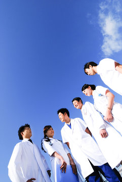 青空を背景に立つ医師・看護師