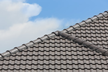 black tile roof of house with blue sky and cloud background