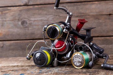 different fishing reels with line on wooden background