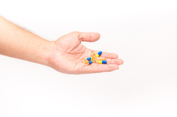 Men hand holding pile of yellow blue tablets