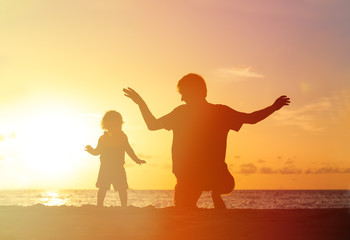 Father and little daughter playing silhouettes at sunset