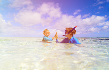 happy mother and son snorkeling on beach