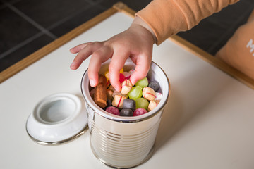 Child takes candy from a jar full of colorful candy