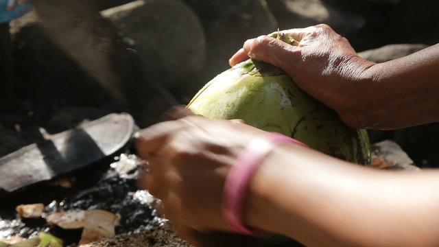 woman opening coconut with big knife